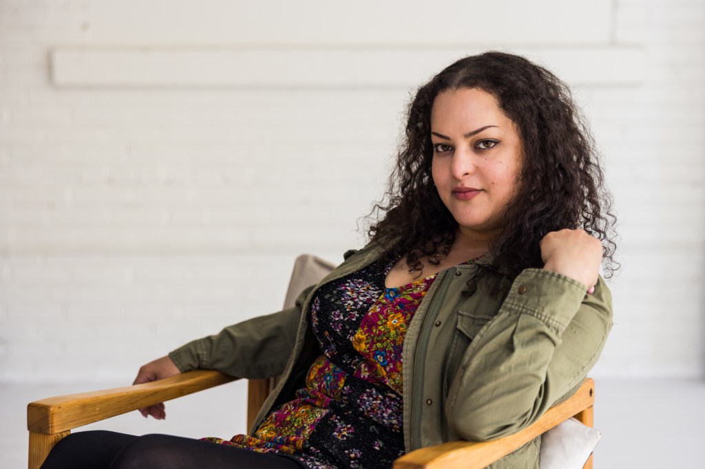 Adebe DeRango-Adem is seated in a chair.