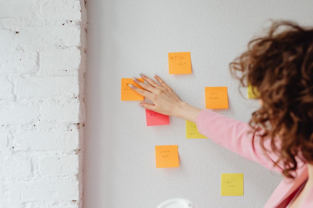 Photo of a woman sticking post-it notes on a white wall.
