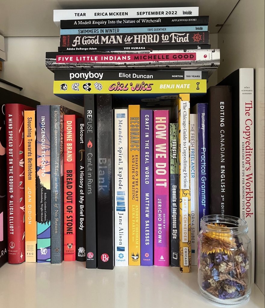 A collection of books (and a jar) on a bookshelf