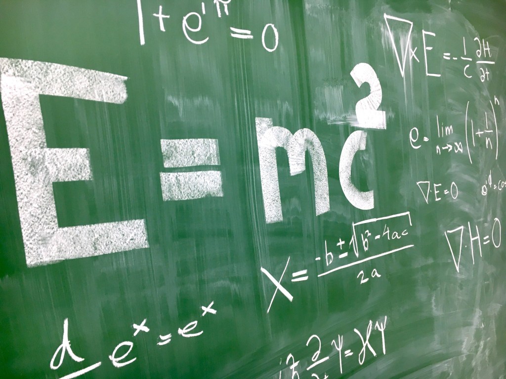 Several math equations written on a  green chalkboard.