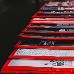 A dozen magazines, lying flat with their (red) edges visible