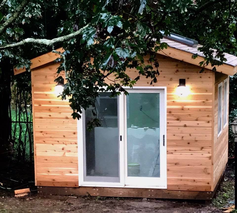 A little wooden cabin under a tree.