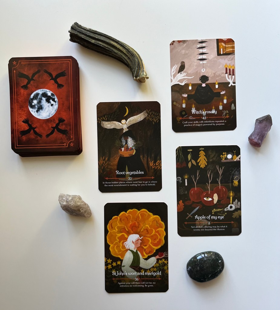 An oracle deck and several oracle cards, along wih several items, such as a stone.