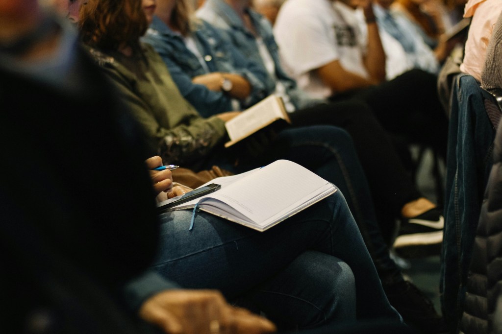 Several people sitting in a meeting with open notebooks.