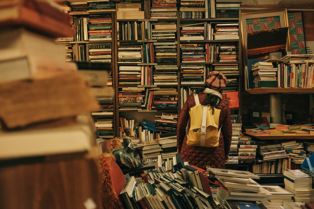 Photo of person with backpack in a library.