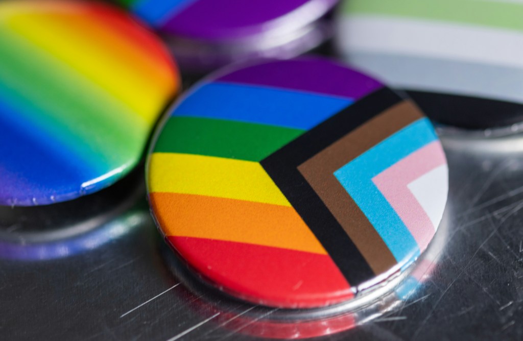 A Progress Pride Pin sits on a desk.