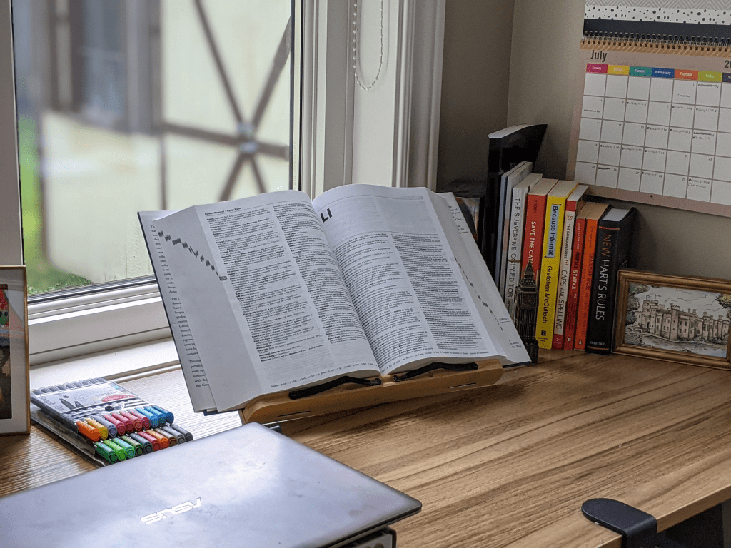 Workspace with open dictionary, pens and books.
