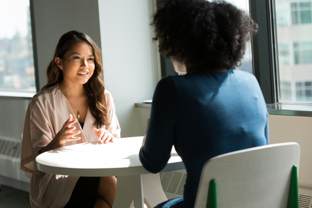 Two women sitting at a table in discussion.