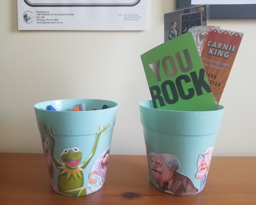 Two Muppet-covered buckets with knickknacks.