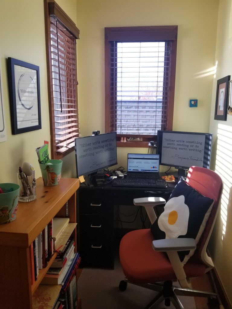 A small office with a desk, laptop and two extra screens.