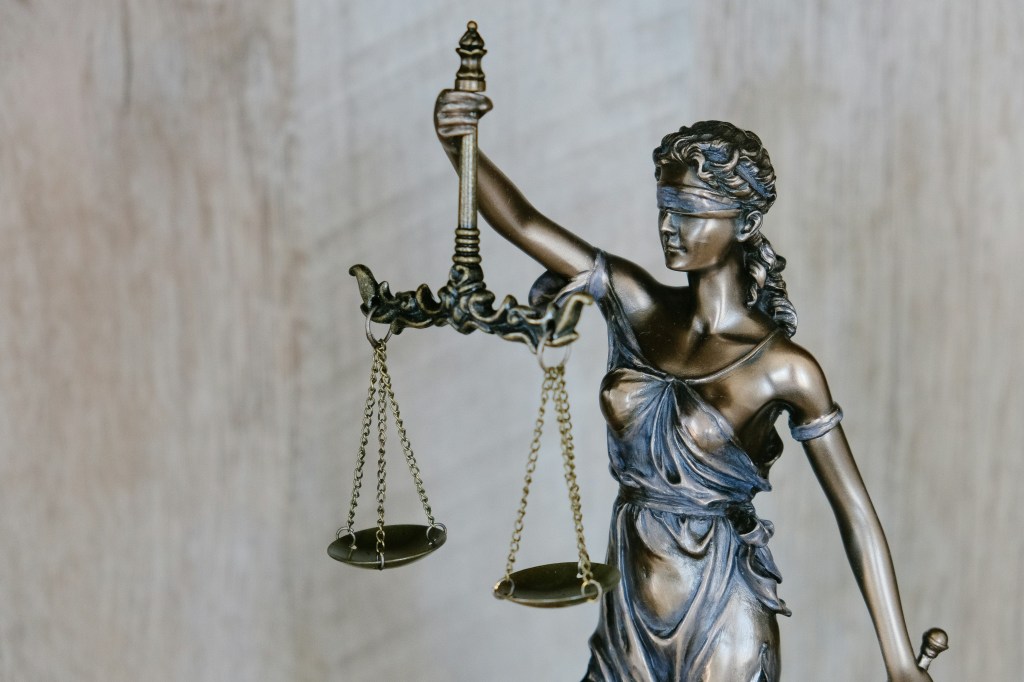 Bronze statue of a blindfolded woman holding imbalanced scales (Lady Justice).